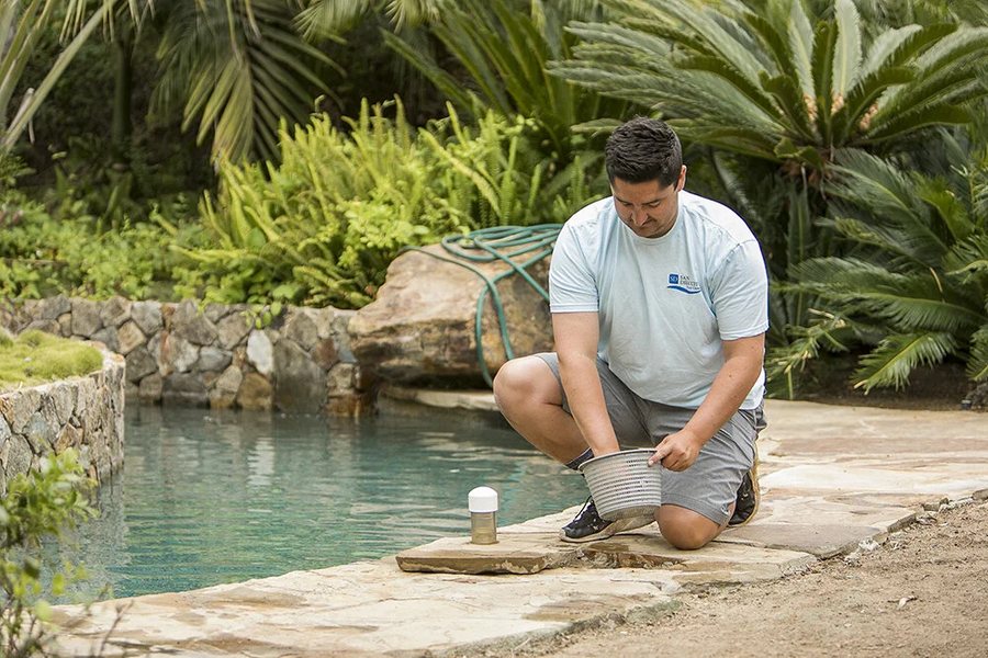 Technician skimming a pool on weekly service in Covina